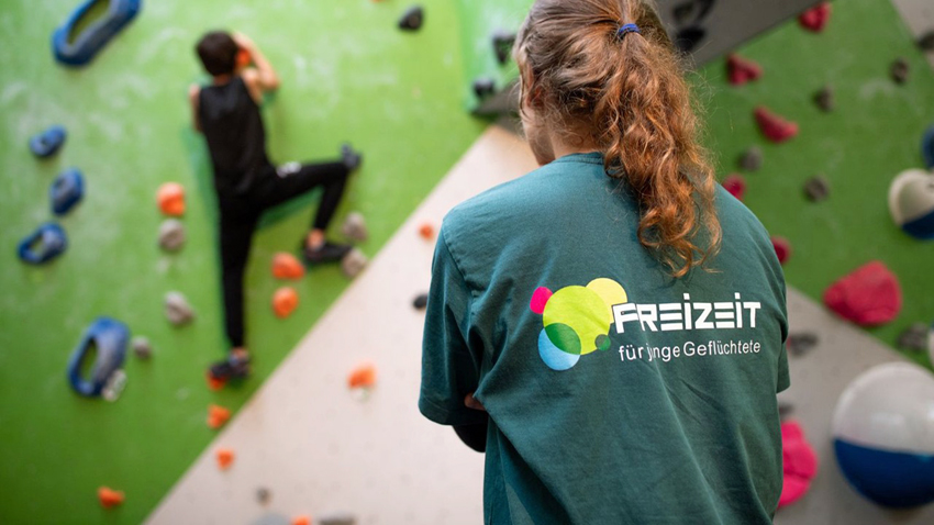  Deborah Berndt, Projektmitarbeiterin von Exil e.V., beobachtet ein Kind beim Klettern – das Projekt „FreiZeit für junge Geflüchtete“ schenkt jungen Bewohner*innen der Erstaufnahme Bewegung, Begegnung und Selbstvertrauen. Foto: Nds. Lotto-Sport-Stiftung/Johannes Krüger